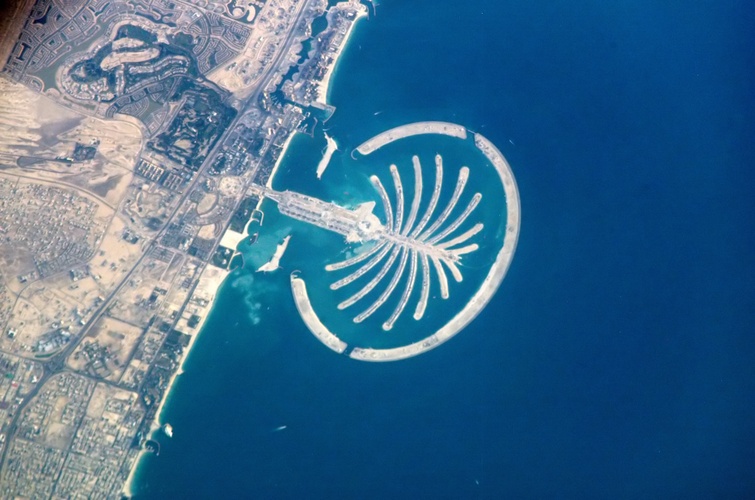 The resort Palm Jumeirah, Dubai, United Arab Emirates, is featured in this image photographed by Expedition 10 Commander Leroy Chiao from the International Space Station in 2005. The resort is under construction on reclaimed land silhouetted against the dark waters of Dubai’s Persian Gulf coast. Advertised as \u0022being visible from the Moon,\u0022 this man\u002Dmade palm\u002Dshaped structure displays 16 huge fronds framed by a 12\u002Dkilometer protective barrier. When completed, the resort will sport 2,000 villas, 40 luxury hotels, shopping centers, cinemas, and other facilities. When completed, the resort is expected to support a population of approximately 500,000 people.