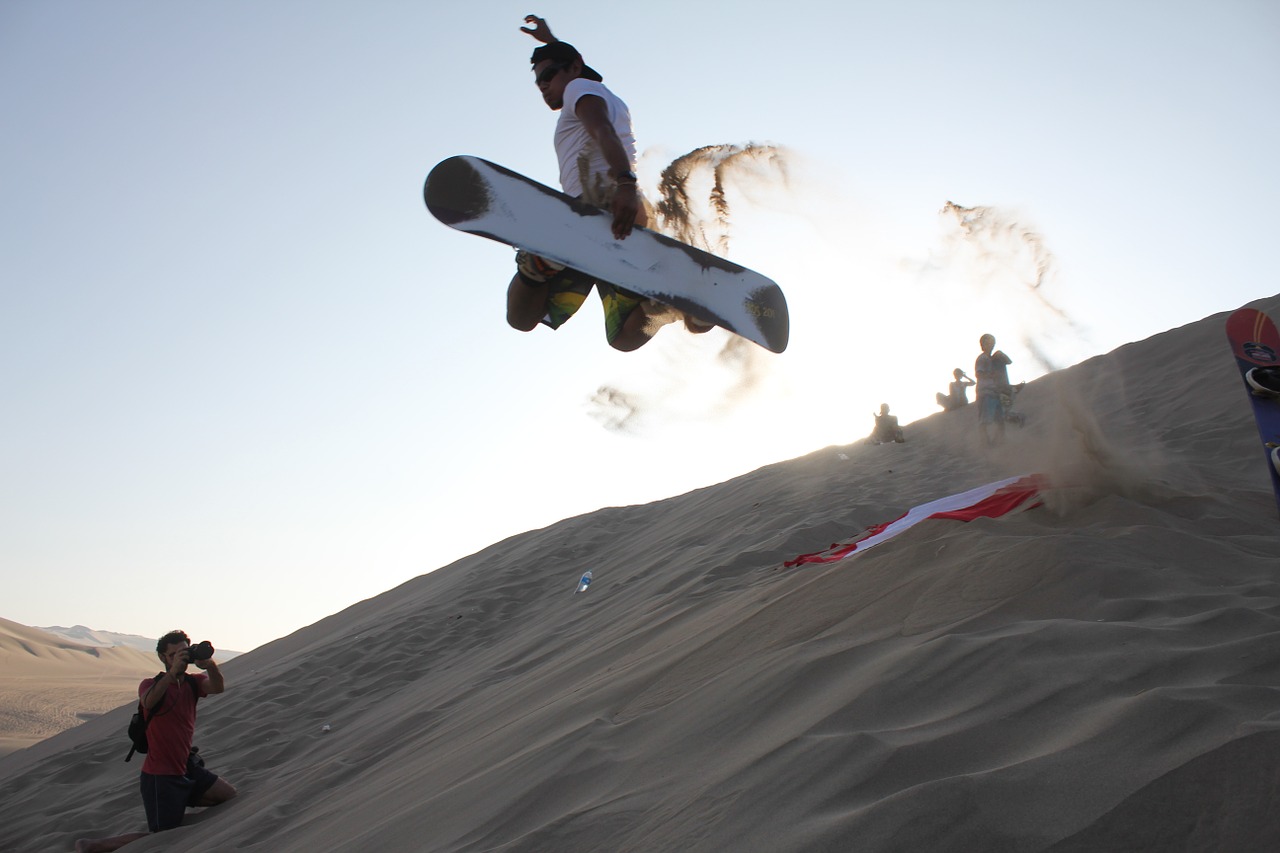 A man sandboarding while others are taking pictures.